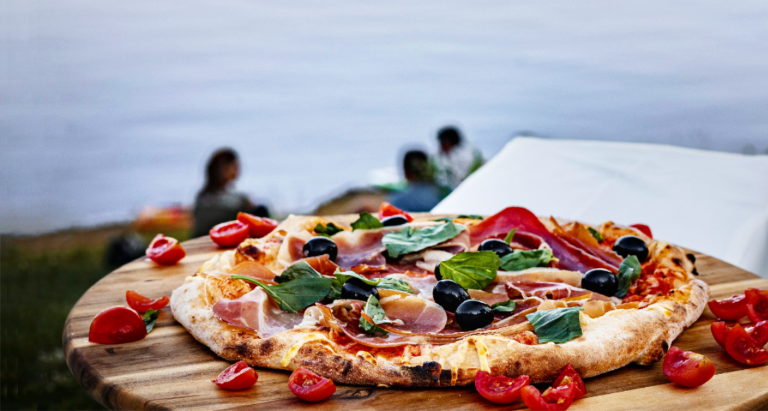 Pizza auf Holzteller draußen am See