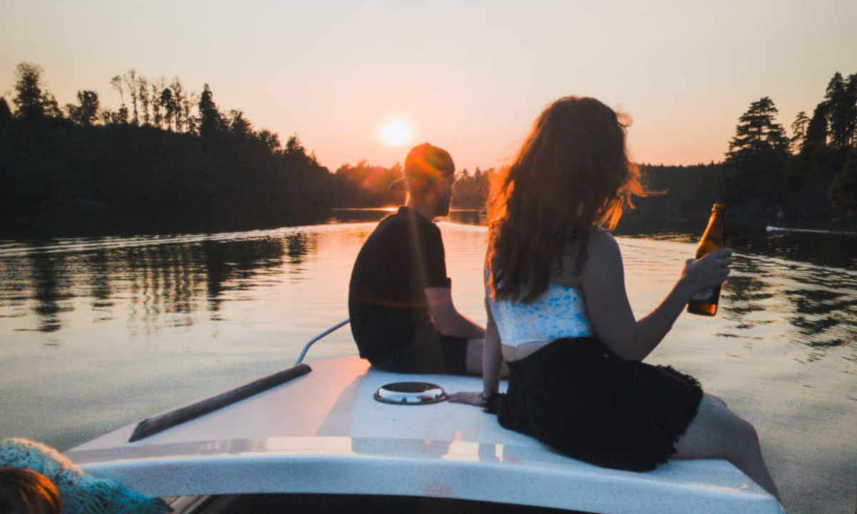 Zwei junge Leute sitzen auf einem E-Boot beim Sonnenuntergang am Stausee Ottenstein